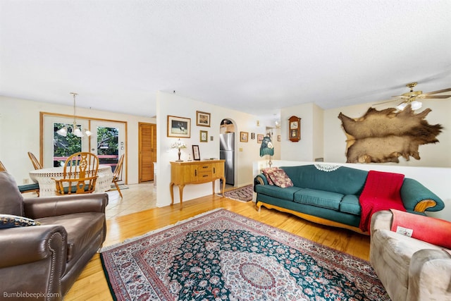 4511 N Stevenson Rd, Otis Orchards, WA 99027 - living room with light wood-type flooring, arched walkways, ceiling fan, a textured ceiling, and a chandelier