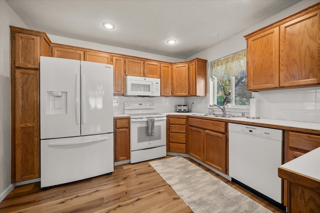 6310 W Sundance Dr, Spokane, WA 99208 - kitchen with white appliances, brown cabinets, backsplash, light countertops, and recessed lighting