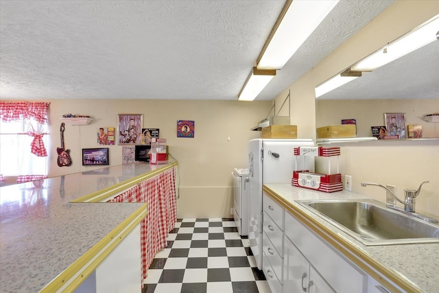 3930 N Deer Lake Rd, Loon Lake, WA 99148 - kitchen featuring dark flooring, light countertops, washing machine and clothes dryer, a textured ceiling, and white cabinetry