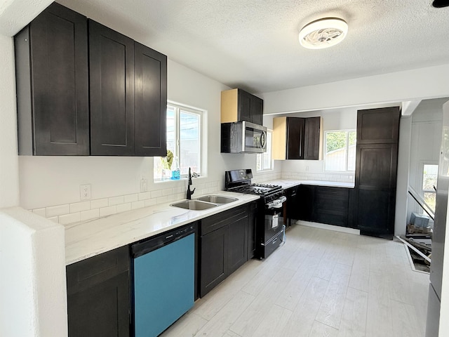 3012 E Wellesley Ave, Spokane, WA 99217 - kitchen with dishwashing machine, stainless steel microwave, black range with gas cooktop, a textured ceiling, and light wood-style floors