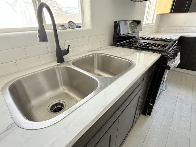 3012 E Wellesley Ave, Spokane, WA 99217 - kitchen with gas range, light stone countertops, dark cabinetry, and light wood-style flooring