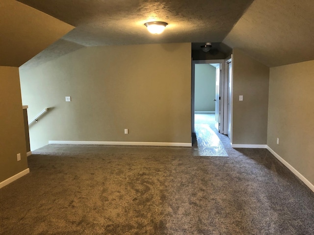 8516 N Summerhill Ln, Spokane, WA 99208 - additional living space with vaulted ceiling, dark carpet, and a textured ceiling