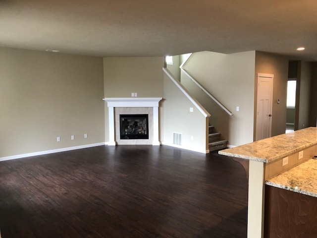 8516 N Summerhill Ln, Spokane, WA 99208 - unfurnished living room featuring dark wood-style flooring, stairs, a tiled fireplace, and recessed lighting