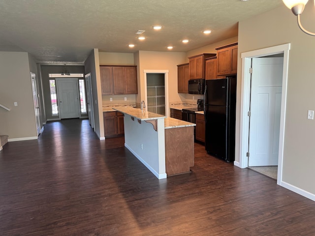 8516 N Summerhill Ln, Spokane, WA 99208 - kitchen with black appliances, dark wood-type flooring, an island with sink, a kitchen breakfast bar, and a textured ceiling