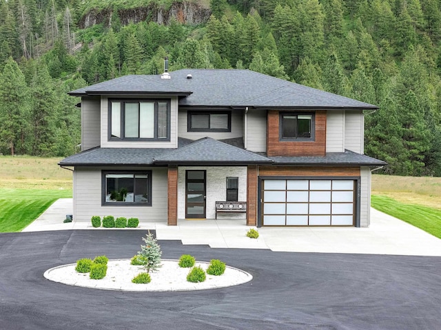 16215 W Coulee Hite Rd, Spokane, WA 99224 - view of front of home featuring asphalt driveway, a forest view, an attached garage, and a shingled roof