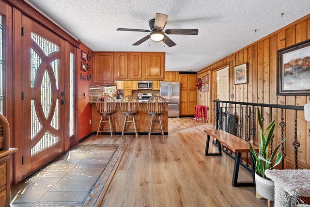 3425 E Upriver Dr, Spokane, WA 99217 - kitchen with stainless steel appliances, light wood-type flooring, a ceiling fan, brown cabinetry, and a peninsula