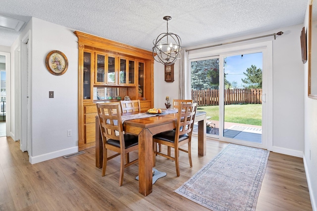 3425 E Upriver Dr, Spokane, WA 99217 - dining area with light wood-type flooring, a textured ceiling, and a chandelier