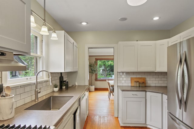 1103 W 20th Ave, Spokane, WA 99203 - kitchen featuring stainless steel appliances, light wood finished floors, white cabinets, decorative backsplash, and recessed lighting