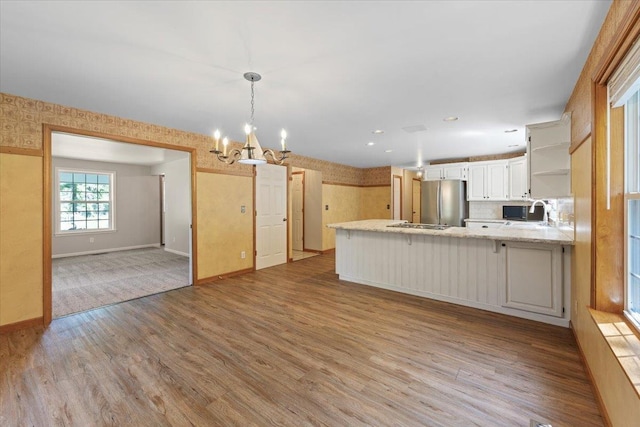 5245A W Prufer Crosscut Rd, Deer Park, WA 99006 - kitchen with freestanding refrigerator, open shelves, a peninsula, a chandelier, and wood finished floors