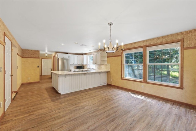 5245A W Prufer Crosscut Rd, Deer Park, WA 99006 - kitchen with freestanding refrigerator, a peninsula, a chandelier, and light wood-style flooring