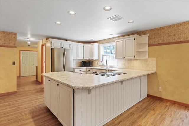 5245A W Prufer Crosscut Rd, Deer Park, WA 99006 - kitchen with freestanding refrigerator, black microwave, light wood-style floors, a peninsula, and light countertops