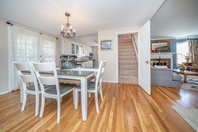 5224 N Post St, Spokane, WA 99204 - dining room featuring a chandelier, stairway, light wood-type flooring, and a fireplace