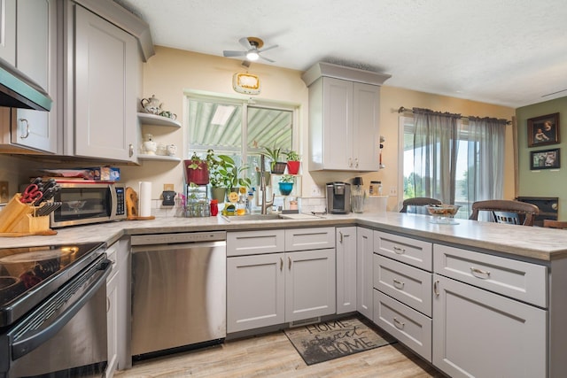 4110 E Ermina Ave, Spokane, WA 99217 - kitchen featuring appliances with stainless steel finishes, a peninsula, light countertops, light wood-style floors, and a textured ceiling
