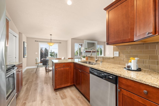 7014 E Columbia Dr, Spokane, WA 99217 - kitchen with stainless steel appliances, a peninsula, decorative backsplash, light wood-style flooring, and brown cabinets