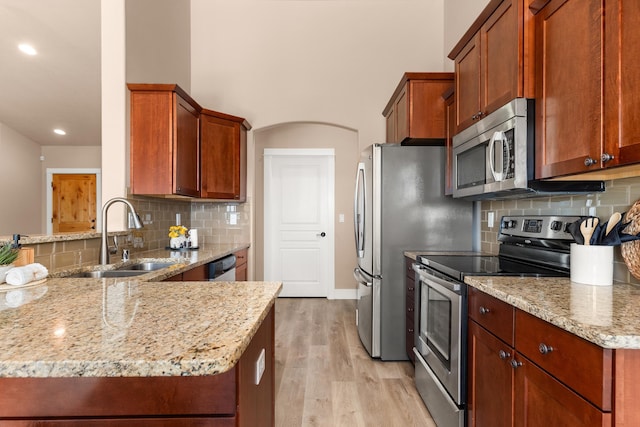 7014 E Columbia Dr, Spokane, WA 99217 - kitchen featuring stainless steel appliances, light wood-style flooring, light stone counters, tasteful backsplash, and a peninsula