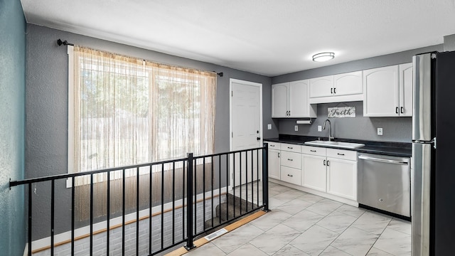 6121 N Belt St, Spokane, WA 99205 - kitchen with appliances with stainless steel finishes, dark countertops, white cabinets, a textured wall, and light marble finish floors
