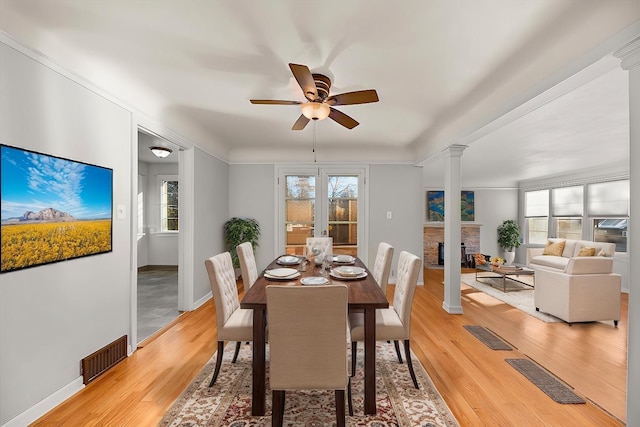 2828 S Arthur St, Spokane, WA 99203 - dining space with decorative columns, ceiling fan, a fireplace, light wood-type flooring, and plenty of natural light