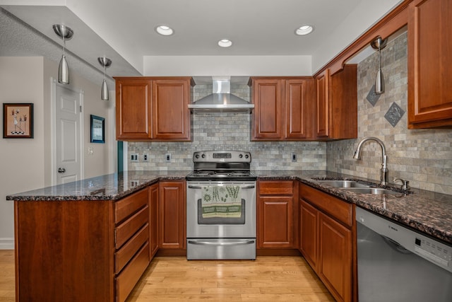 11912 N Atlantic St, Spokane, WA 99218 - kitchen featuring stainless steel appliances, wall chimney range hood, a peninsula, light wood-style floors, and dark stone countertops