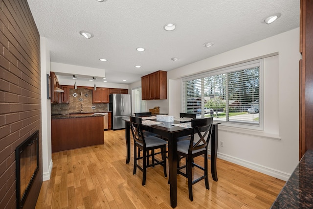 11912 N Atlantic St, Spokane, WA 99218 - dining area featuring light wood-style flooring, a textured ceiling, a fireplace, and recessed lighting