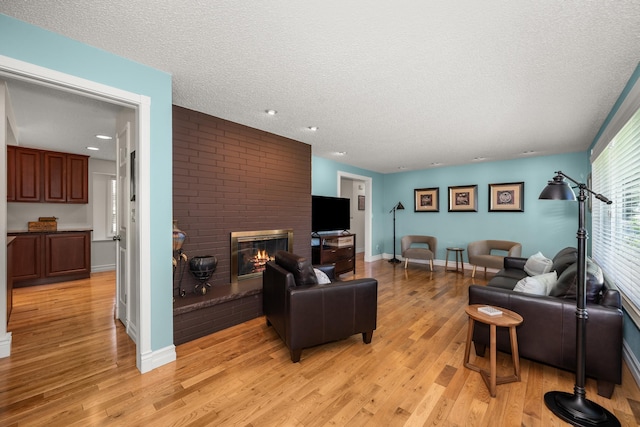 11912 N Atlantic St, Spokane, WA 99218 - living room featuring a fireplace, light wood-style floors, a textured ceiling, and recessed lighting