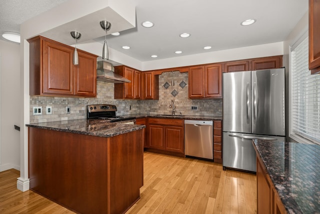 11912 N Atlantic St, Spokane, WA 99218 - kitchen with appliances with stainless steel finishes, wall chimney exhaust hood, light wood finished floors, a peninsula, and tasteful backsplash