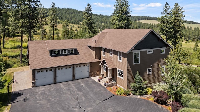 7116 S Linke Rd, Greenacres, WA 99016 - view of front facade with asphalt driveway, a garage, a forest view, stone siding, and roof with shingles