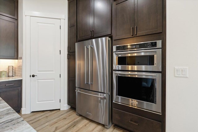 12918 E San Juan Ln, Spokane, WA 99206 - kitchen featuring stainless steel appliances, dark brown cabinetry, light wood-type flooring, and light stone countertops