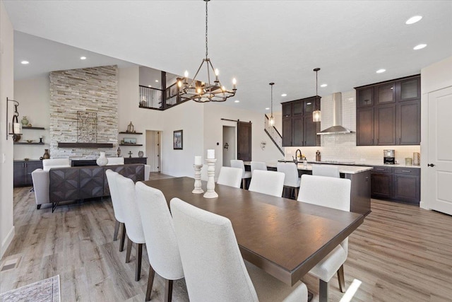 12918 E San Juan Ln, Spokane, WA 99206 - dining room featuring a barn door, light wood finished floors, recessed lighting, a chandelier, and a stone fireplace