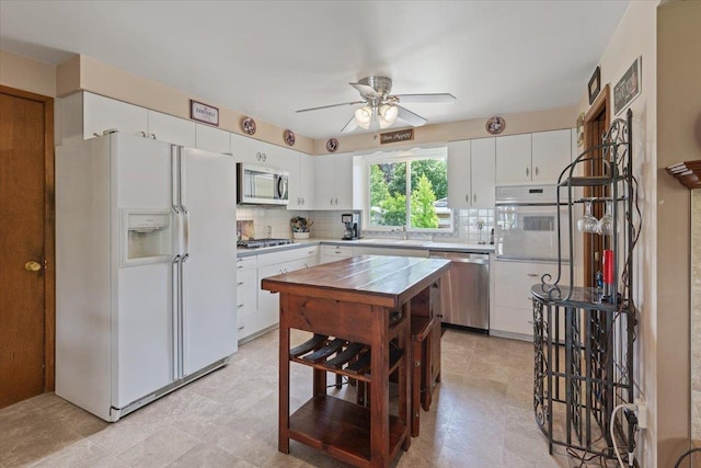 2515 E 38th Ave, Spokane, WA 99223 - kitchen featuring appliances with stainless steel finishes, tasteful backsplash, ceiling fan, light countertops, and white cabinetry