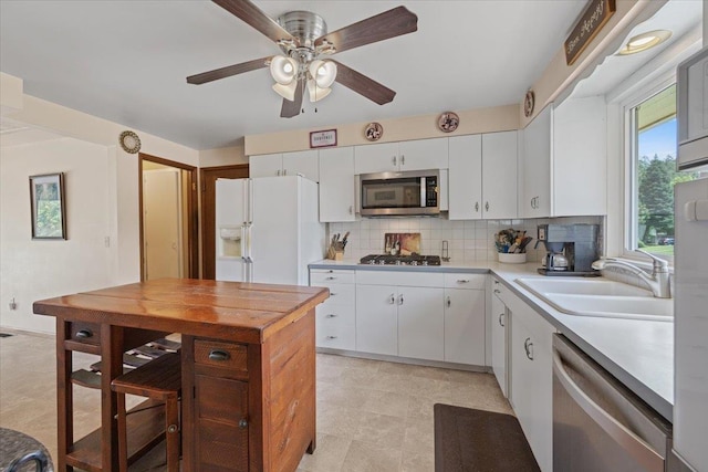 2515 E 38th Ave, Spokane, WA 99223 - kitchen with stainless steel appliances, light countertops, decorative backsplash, a ceiling fan, and white cabinetry