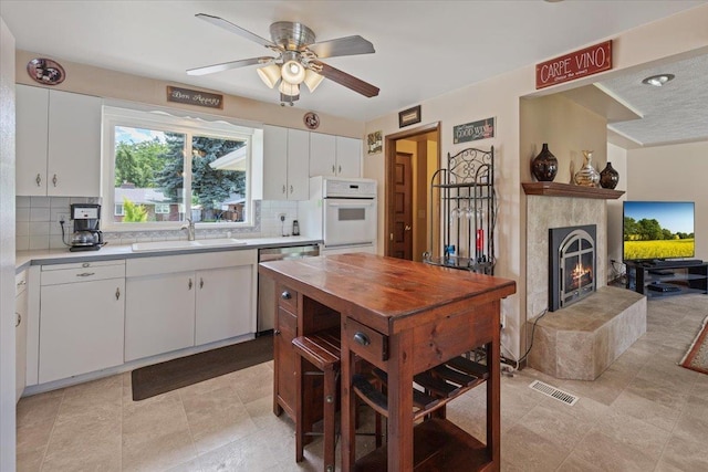 2515 E 38th Ave, Spokane, WA 99223 - kitchen featuring dishwasher, white oven, backsplash, white cabinetry, and a ceiling fan