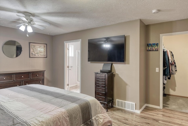 4318 N Upland Ct, Spokane Valley, WA 99216 - bedroom featuring a walk in closet, light wood finished floors, connected bathroom, a textured ceiling, and a ceiling fan