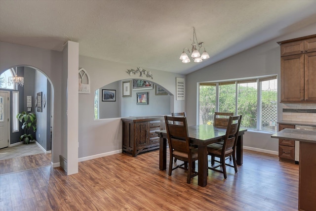 4318 N Upland Ct, Spokane Valley, WA 99216 - dining area featuring a chandelier, arched walkways, wood finished floors, lofted ceiling, and a textured ceiling