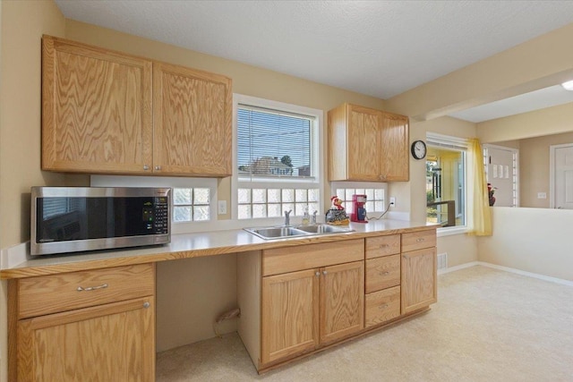 34 E Euclid Ave, Spokane, WA 99207 - kitchen with stainless steel microwave, light brown cabinetry, light countertops, and light colored carpet