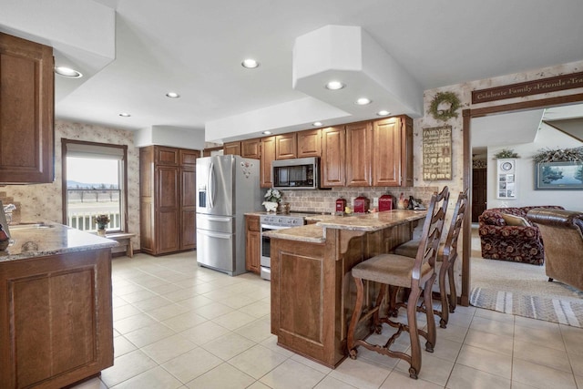 3333 N Ashton Rd, Otis Orchards, WA 99027 - kitchen featuring appliances with stainless steel finishes, a peninsula, light tile patterned floors, recessed lighting, and light stone counters
