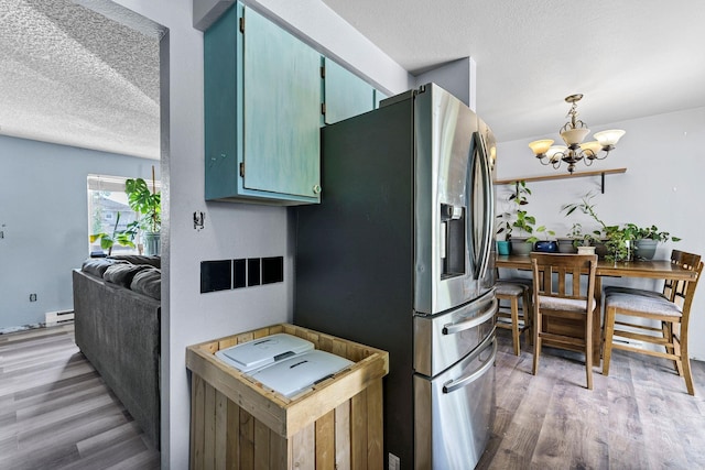 15217 E 15th Ave, Spokane Valley, WA 99037 - kitchen featuring stainless steel fridge, wood finished floors, a chandelier, a textured ceiling, and baseboard heating