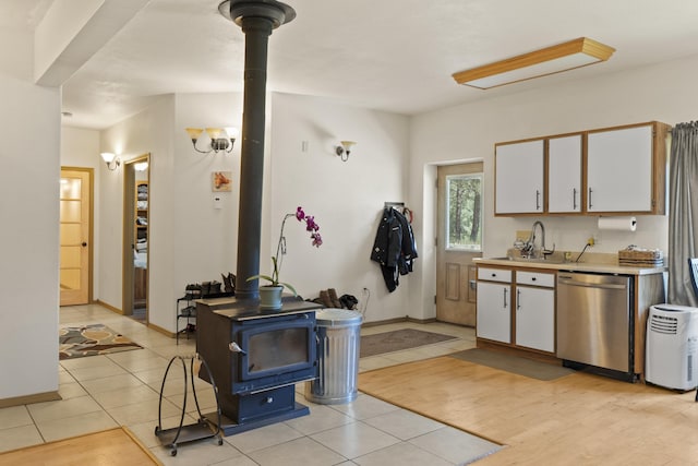 20902 S Ritchey Rd, Spokane, WA 99004 - kitchen with stainless steel dishwasher, a wood stove, white cabinetry, light countertops, and light tile patterned floors
