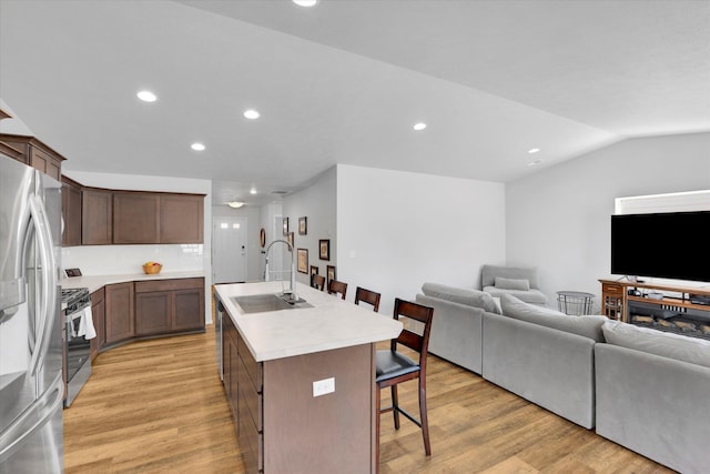 10521 W Salmonberry Rd, Cheney, WA 99004 - kitchen with appliances with stainless steel finishes, open floor plan, a kitchen bar, light wood-style floors, and a kitchen island with sink
