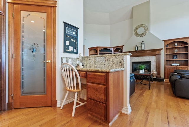 8708 E Redwood Ln, Spokane, WA 99217 - kitchen featuring light wood-style floors, light stone counters, a high end fireplace, and brown cabinets