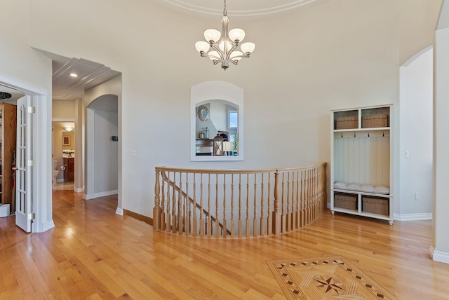 8708 E Redwood Ln, Spokane, WA 99217 - hall with wood finished floors, a chandelier, arched walkways, and an upstairs landing