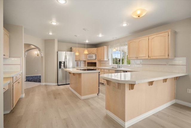 6419 W Skagit Ave, Spokane, WA 99208 - kitchen featuring appliances with stainless steel finishes, light brown cabinetry, arched walkways, a breakfast bar, and recessed lighting