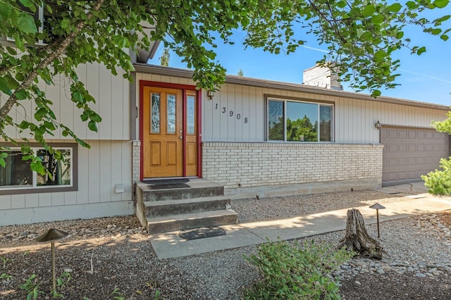 13908 E 32nd Ave, Spokane Valley, WA 99037 - doorway to property with an attached garage, a chimney, and brick siding