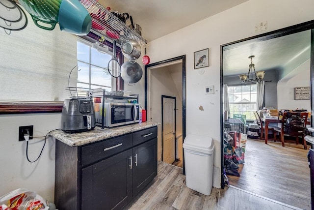 803 E Queen Ave, Spokane, WA 99207 - kitchen featuring stainless steel microwave, light wood-style flooring, a chandelier, light countertops, and dark cabinets