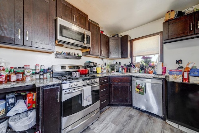 803 E Queen Ave, Spokane, WA 99207 - kitchen featuring stainless steel appliances, light wood finished floors, dark brown cabinetry, and light stone counters