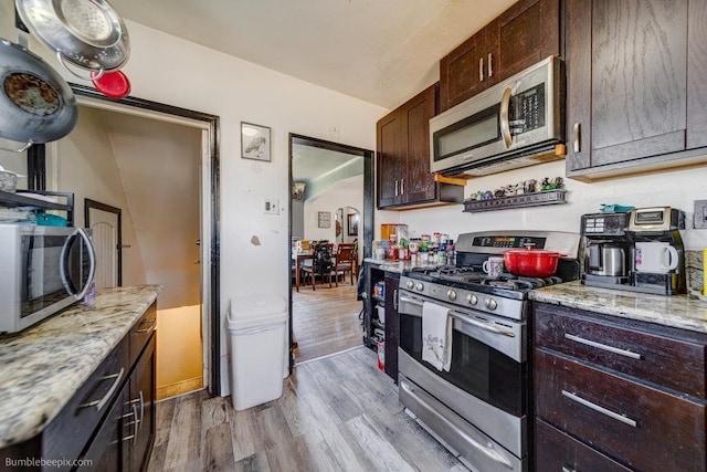 803 E Queen Ave, Spokane, WA 99207 - kitchen with stainless steel appliances, light wood-style floors, dark brown cabinets, and light stone counters