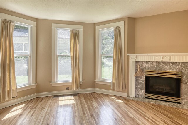 1428 E 18th Ave, Spokane, WA 99203 - unfurnished living room featuring wood finished floors, a premium fireplace, healthy amount of natural light, and a textured ceiling