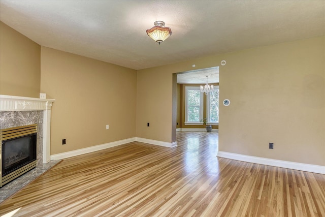 1428 E 18th Ave, Spokane, WA 99203 - unfurnished living room with light wood-style flooring, a chandelier, and a fireplace