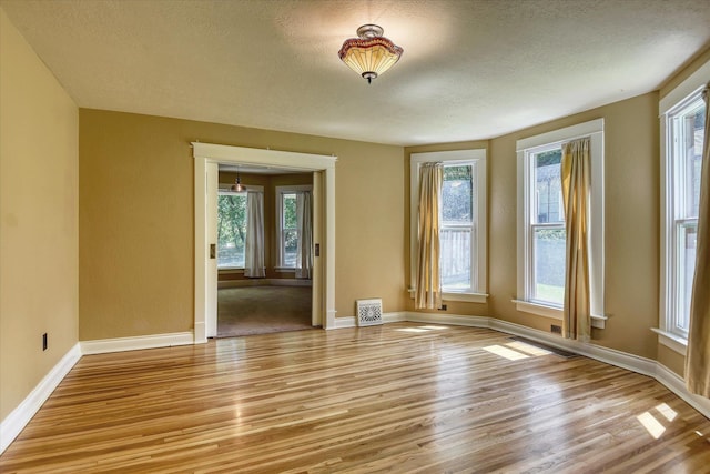 1428 E 18th Ave, Spokane, WA 99203 - empty room with plenty of natural light, light wood-style floors, and a textured ceiling
