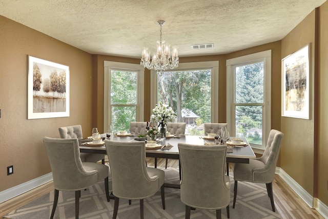 1428 E 18th Ave, Spokane, WA 99203 - dining room featuring wood finished floors, a chandelier, a textured ceiling, healthy amount of natural light, and a textured wall