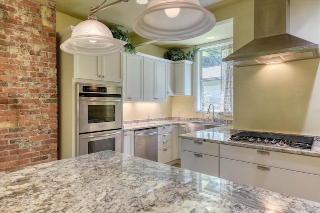 1428 E 18th Ave, Spokane, WA 99203 - kitchen featuring wall chimney exhaust hood, stainless steel appliances, light stone countertops, white cabinetry, and brick wall